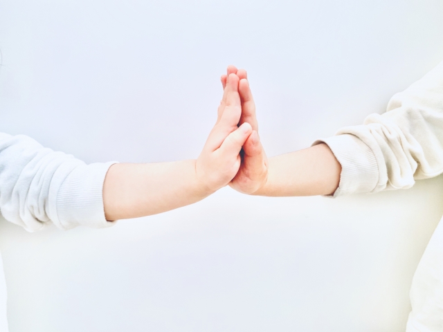 2人で手を合わせるX子どもの手